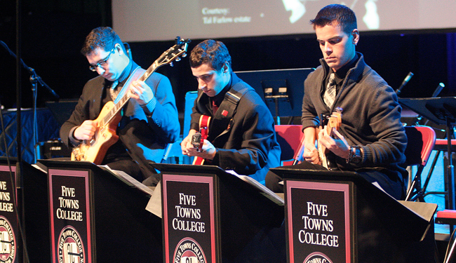 Three DMA music students play guitars in performance.